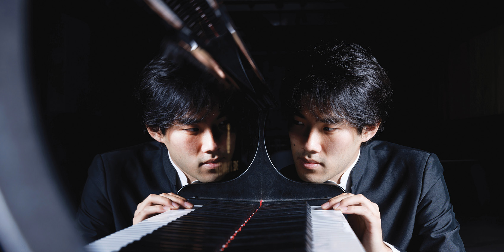 Pianist Bruce Liu reflected in the polished surface of a grand piano