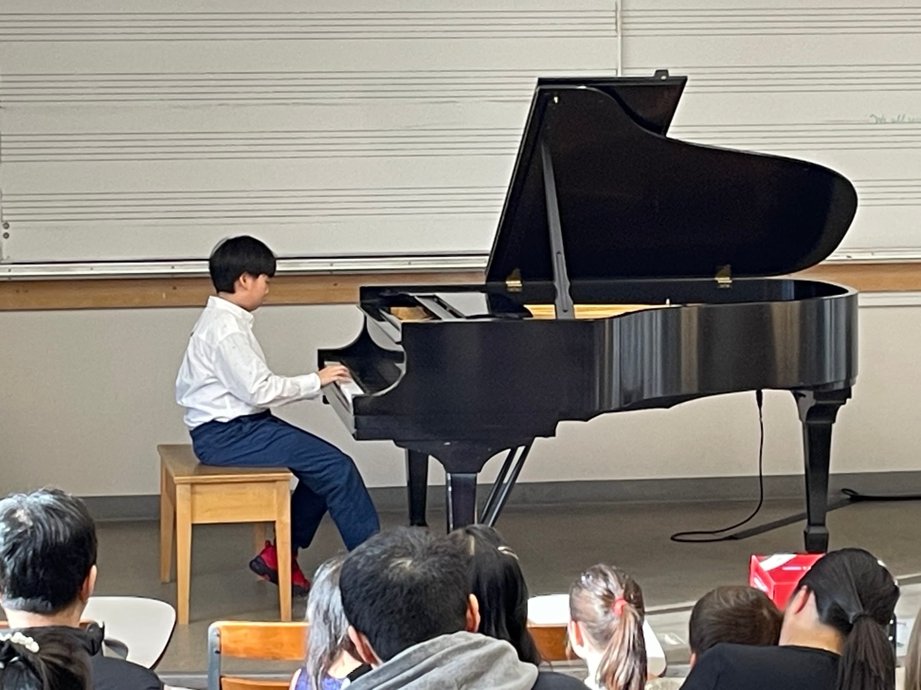 A student performing at a grand piano during the Winter Studio Recital