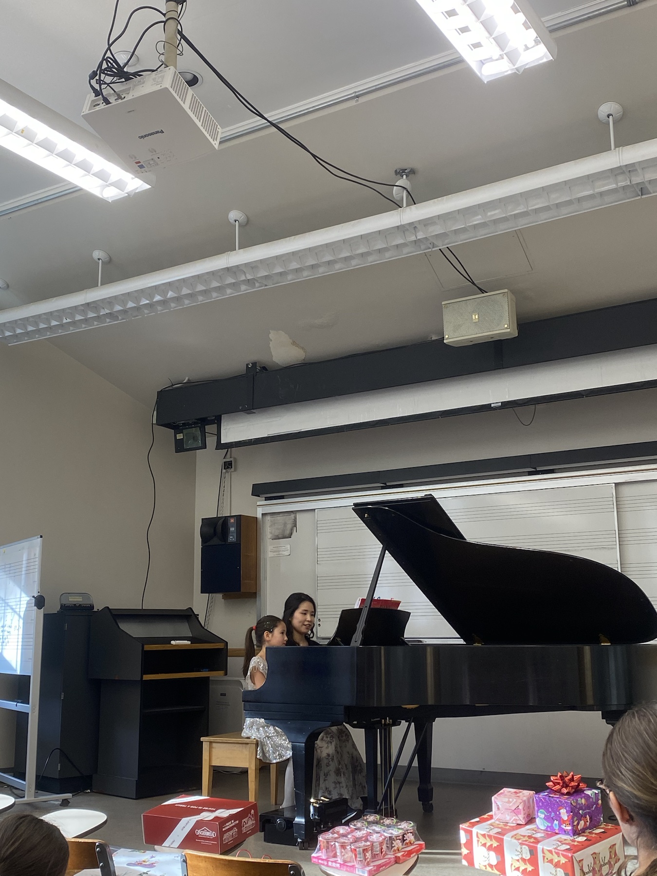 Chiao-Yu Wu seated at the piano with a young student