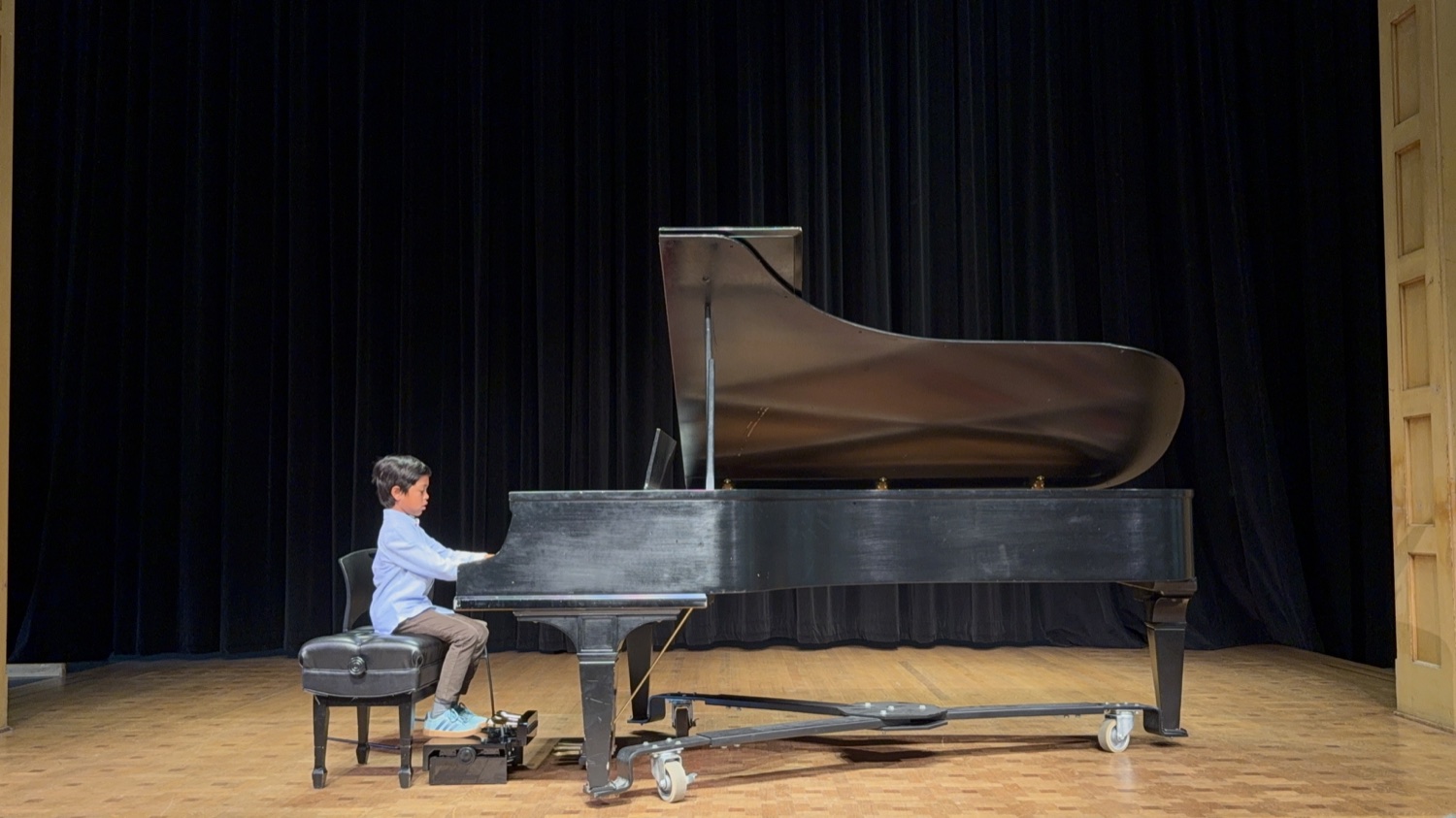 A young pianist performing solo on the recital stage