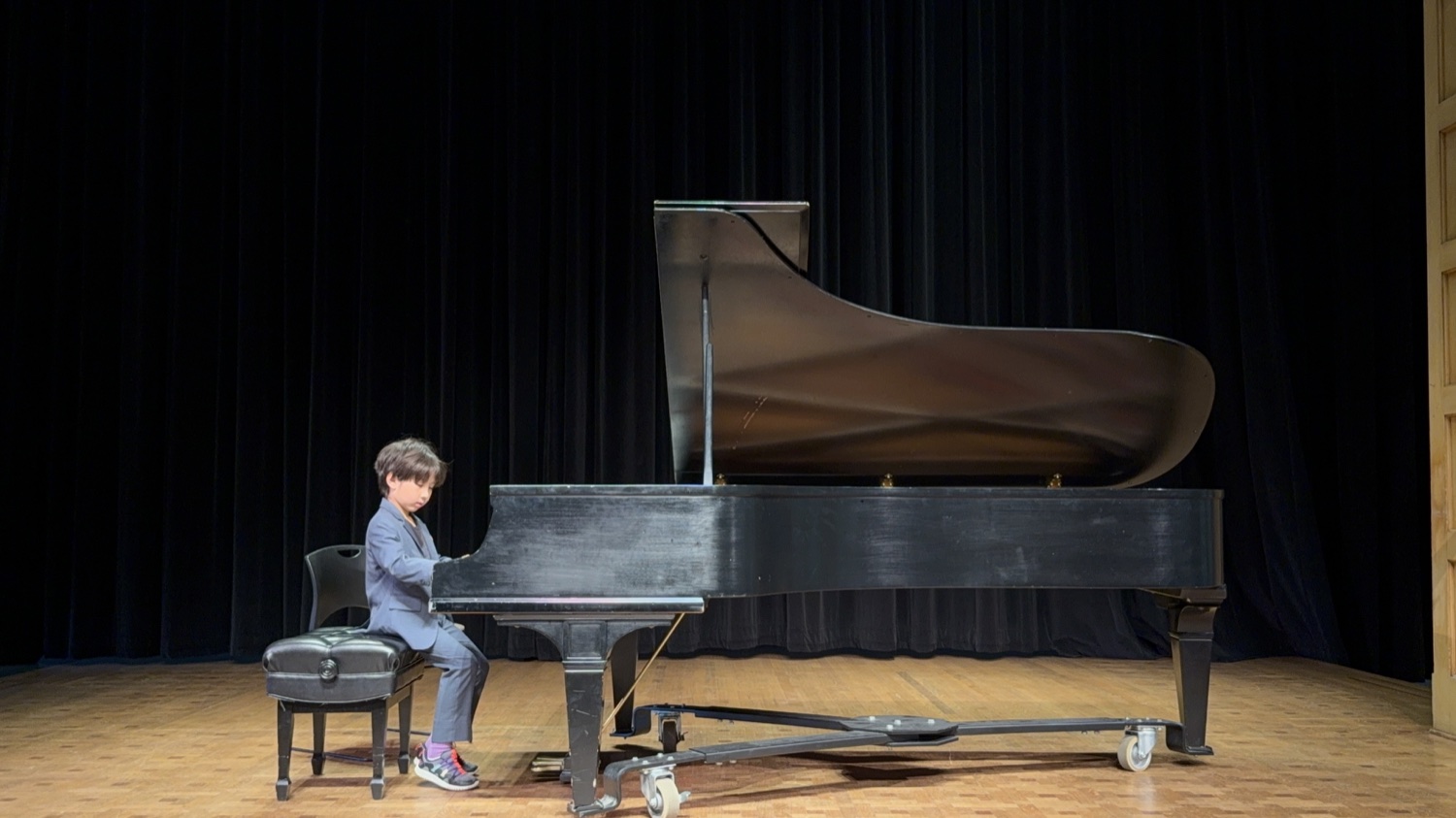 A young pianist in concert attire performing on stage