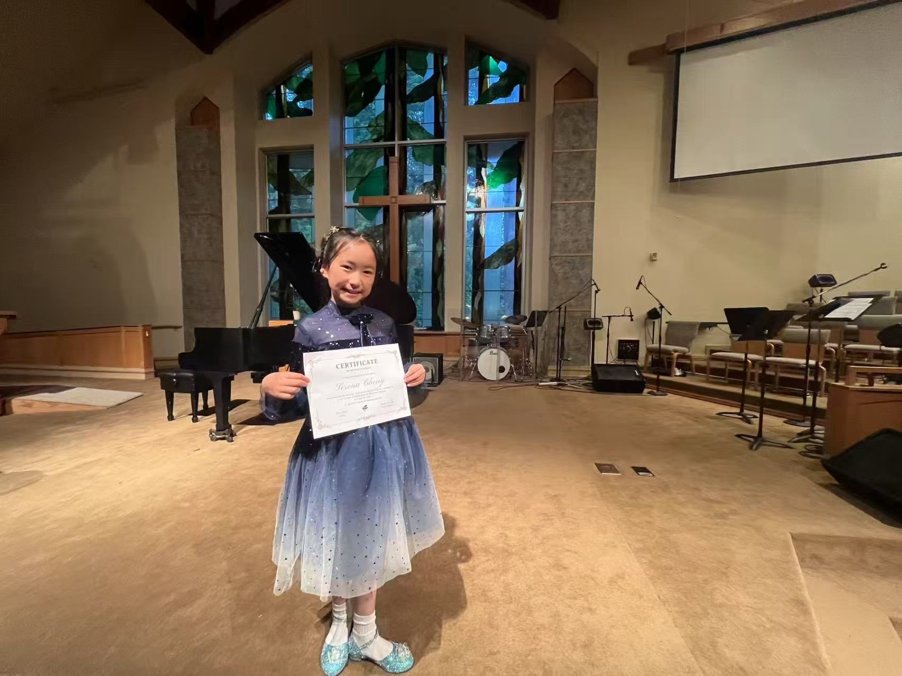 A student proudly holding her certificate after the Spring Studio Recital